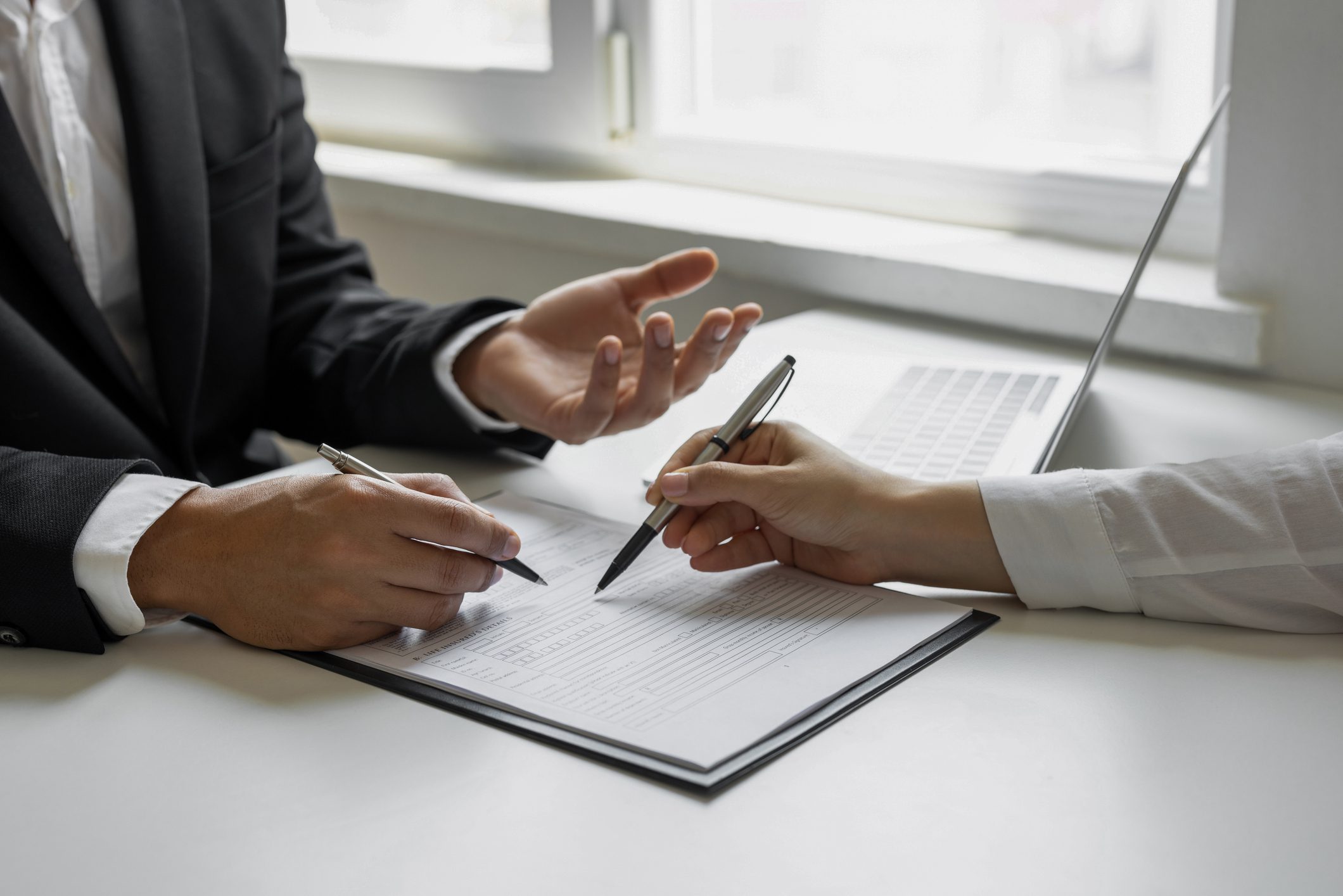 Hands exchanging pens over paperwork