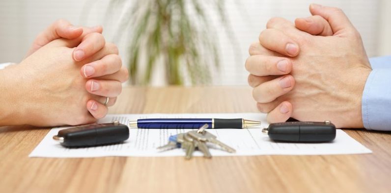 Hands folded over divorce papers and keys