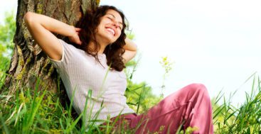 Woman relaxing against a tree outdoors
