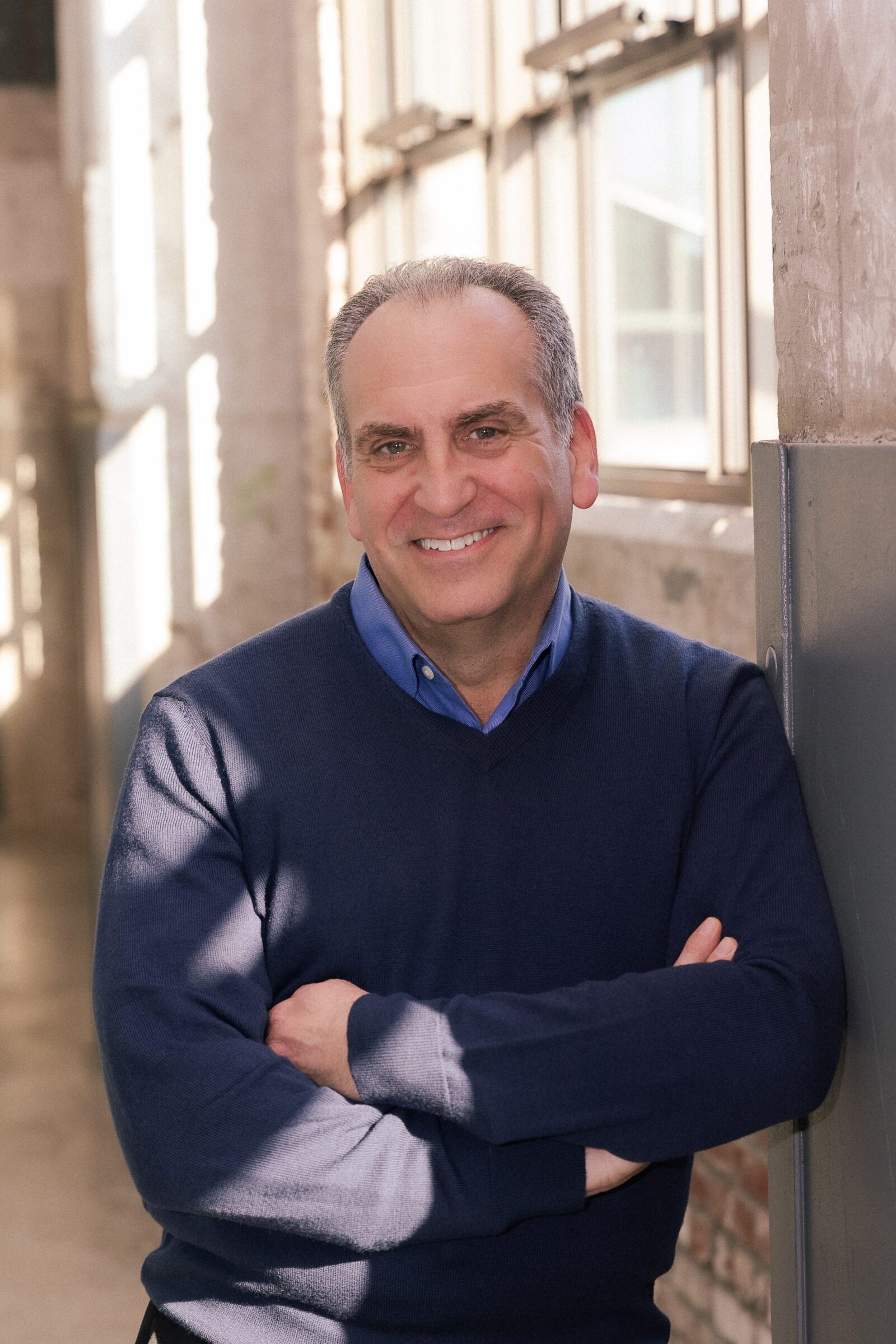 Smiling man standing by sunlit window.