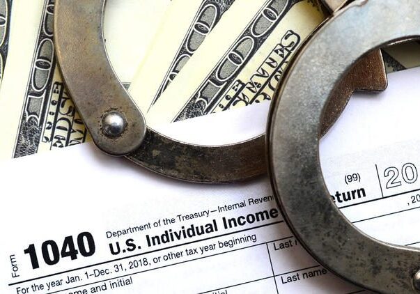 Handcuffs on tax form and dollar bills
