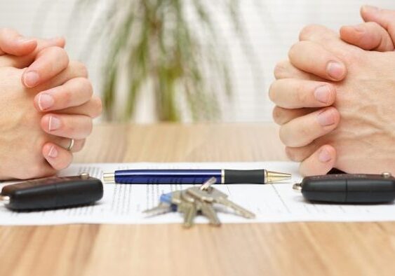 Hands folded over divorce papers and keys