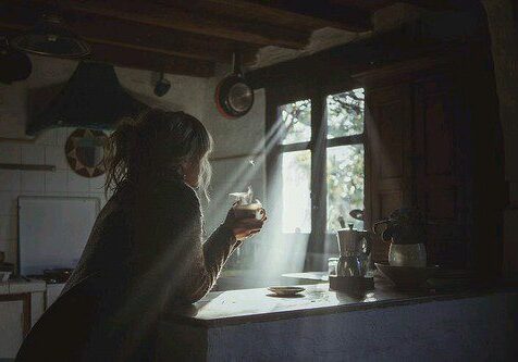 Person enjoying coffee in sunlit kitchen